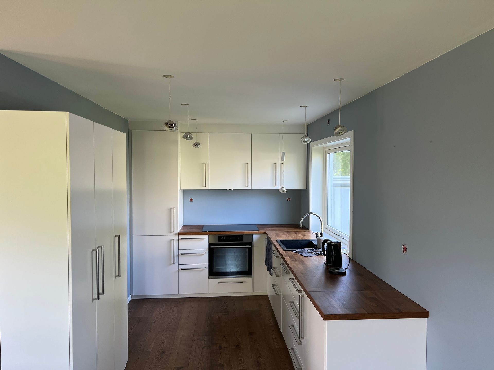 Modern kitchen with white cabinets, wooden countertops, and blue walls.